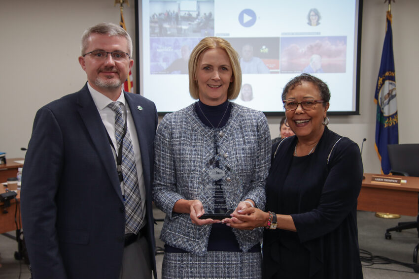 Meredith Rozanski holds a glass trophy while standing with Robbie Fletcher and Sharon Porter Robinson.